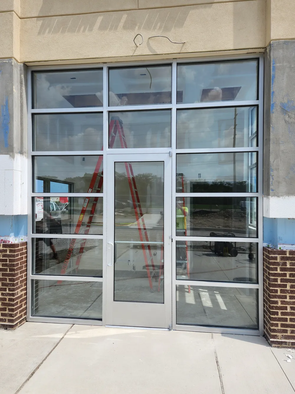 Clear anodized aluminum storefront entrance with a glazed door, sidelites, and transoms