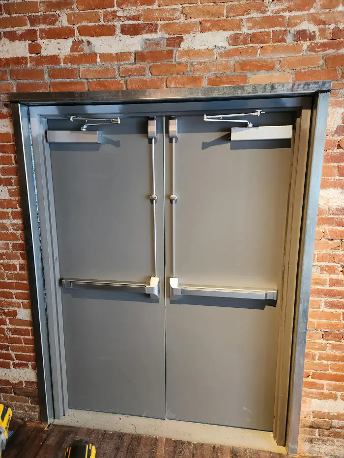 Hollow metal double doors and frame with exit devices in an exposed brick opening