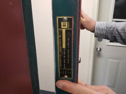 Fire door label being examined at the edge of an opening