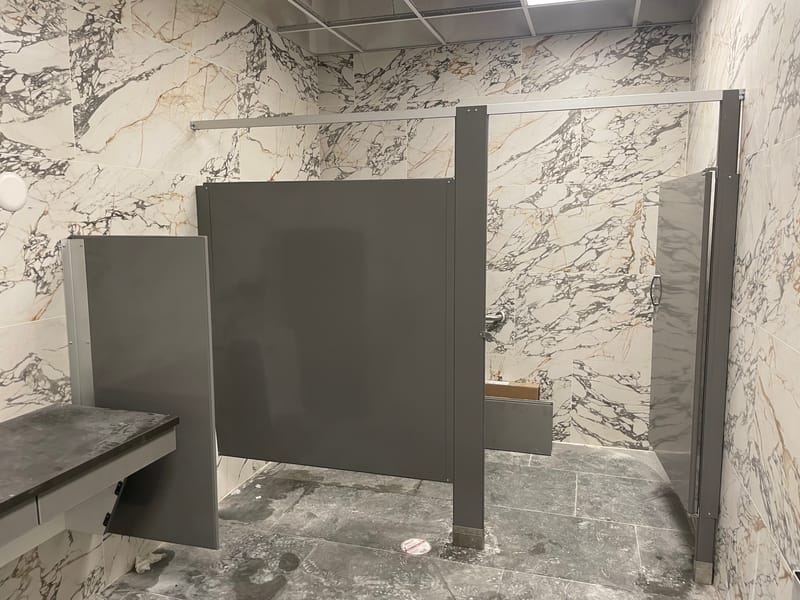 Gray toilet partition door and panels beside a restroom counter - Stow, OH